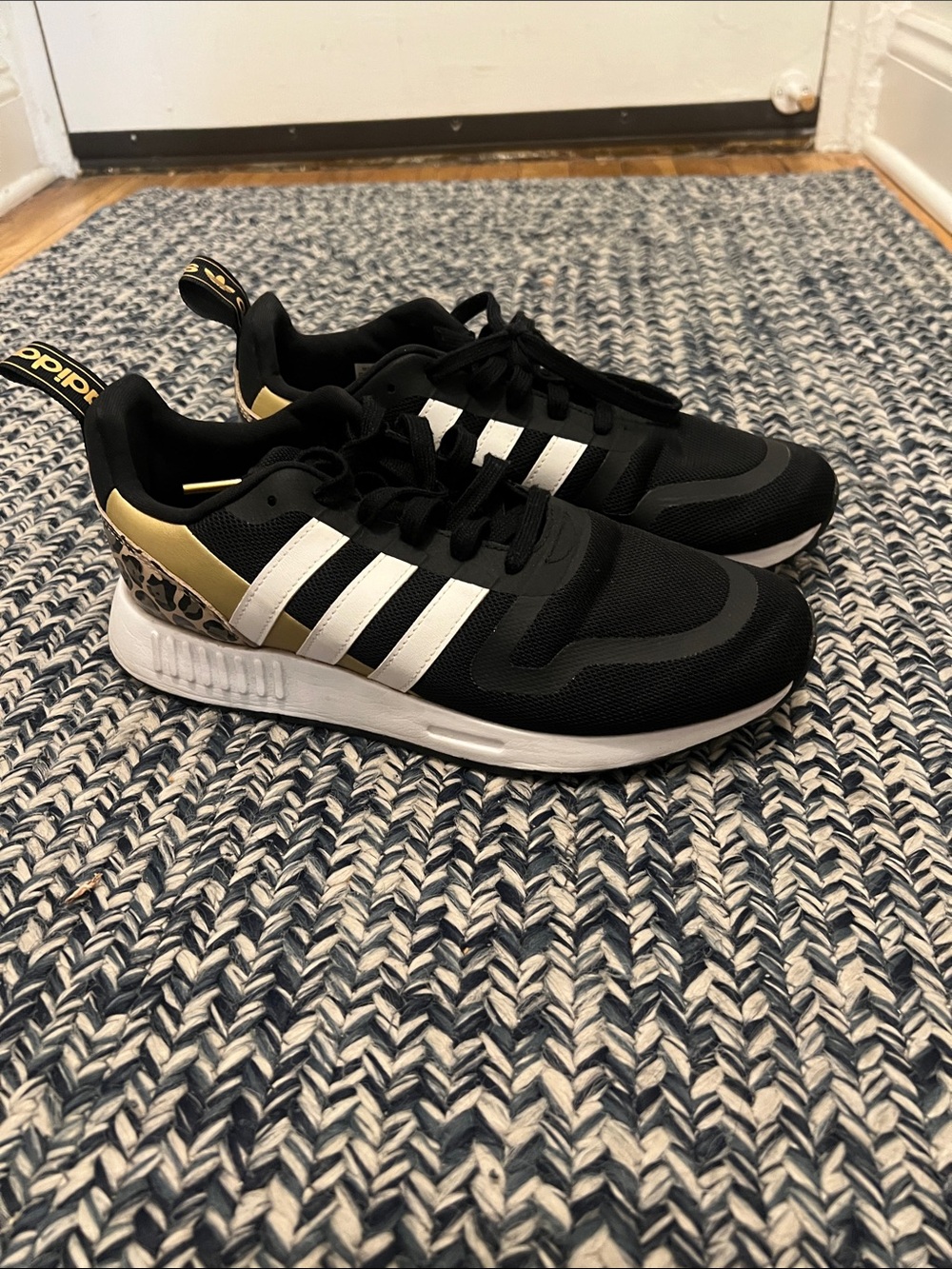 Adidas Black Sneakers with White Stripes and Gold Heel Accent